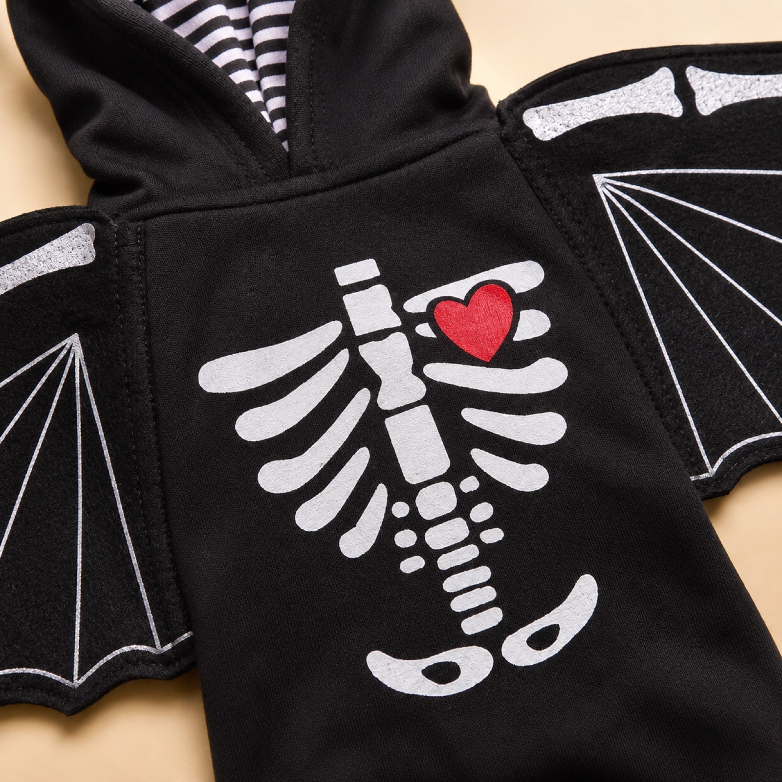 Close-up detail of the skeleton ribcage print, red heart, hood and detachable bat wings